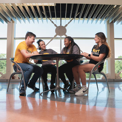 four students sitting around a table conversing