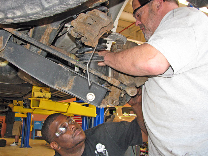 Student working on spring on car