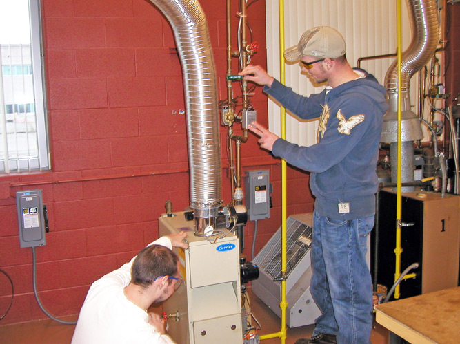 Two students in lab doing furnace repair