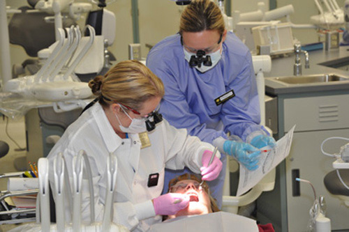 Faculty demonstrating teeth cleaning to student