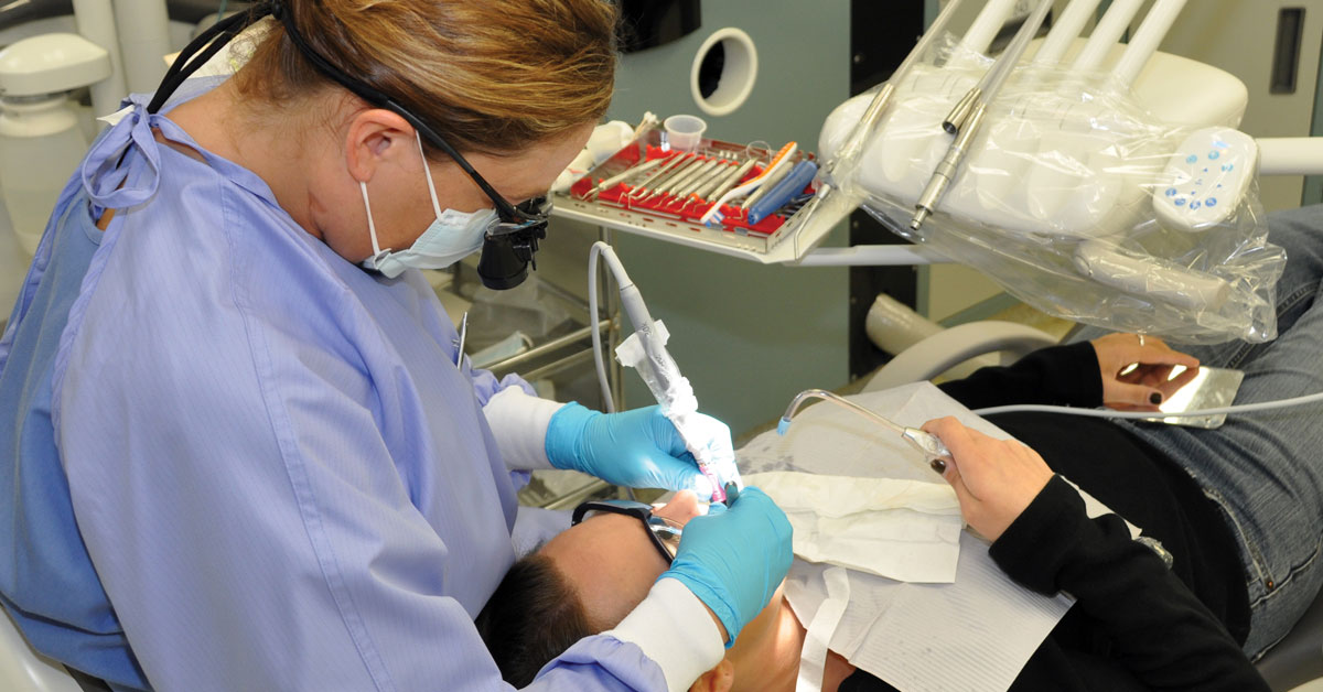 Dental Hygiene student cleaning client teeth in the dental hygiene lab