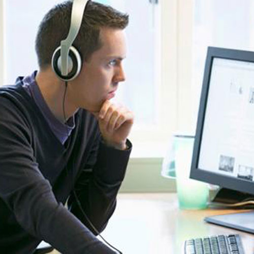 male with headphones looking at a computer
