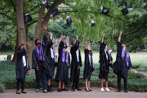 college students in graduation regalia throwing thier motar caps in the air