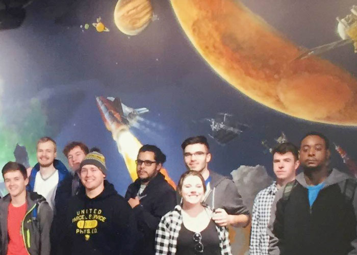 Group of students in front of a mural of the solar system