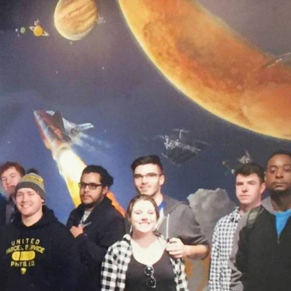 Group of students in front of a mural of the solar system
