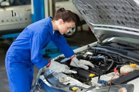 Female mechanic working under the hood of a car
