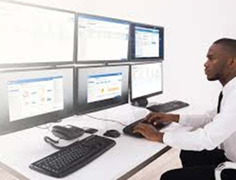 Young black male working with computer at a desk with multiple computer screens