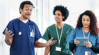 Young man and two young women in medical scrubs conversing